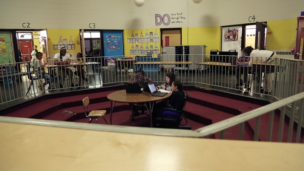 This photo shows a large, indoor, open space being used simultaneously for two small instructional groups and a one-on-one session.