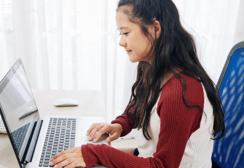 Student works on laptop, sitting at home desk
