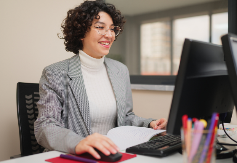 Woman sits in front of computer, smiling
