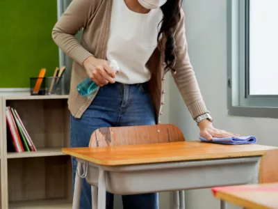 Teacher cleaning a desk inside classroom
