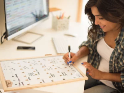 A woman sitting at a desk writing on a board of a calendar
