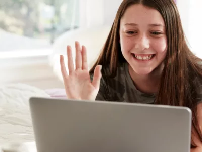 A girl is smiling while looking at a laptop
