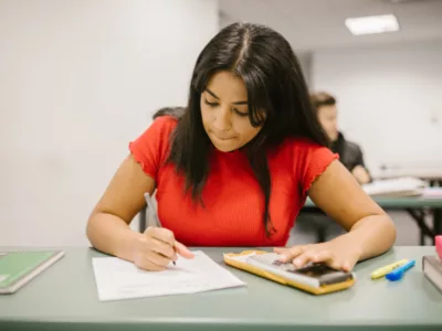 A student sitting at a desk writing on a piece of paper
