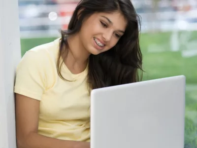 Student smiles at laptop screen
