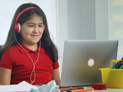 Student wearing headphones smiles at laptop
