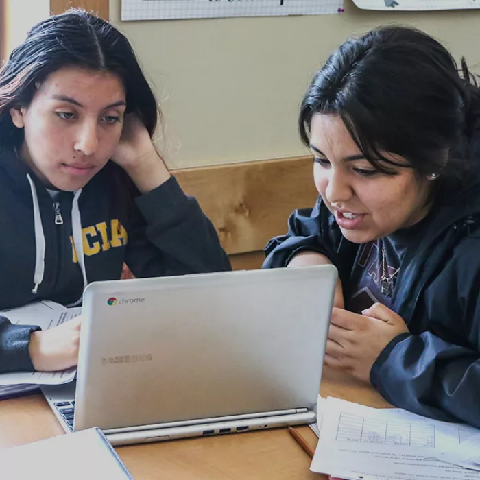 Two students look at laptop together
