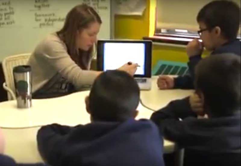 Photo of teacher explaining content from laptop to a group of students
