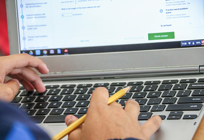 Closeup of person typing at laptop keyboard with a pencil in hand
