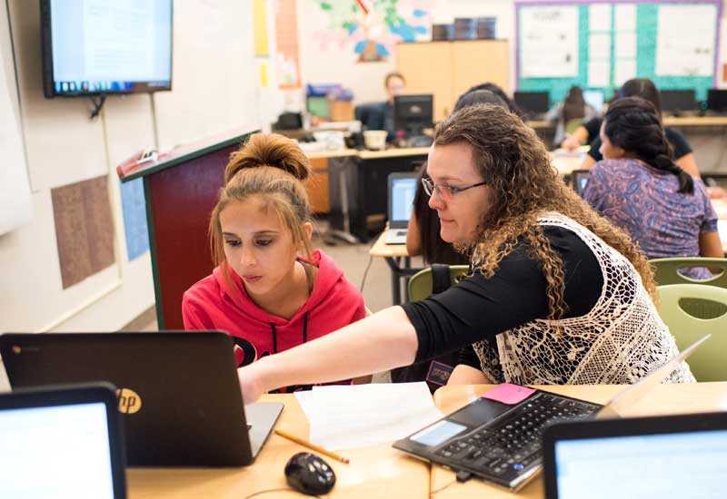 Photo of teacher and student working together in front of lap top
