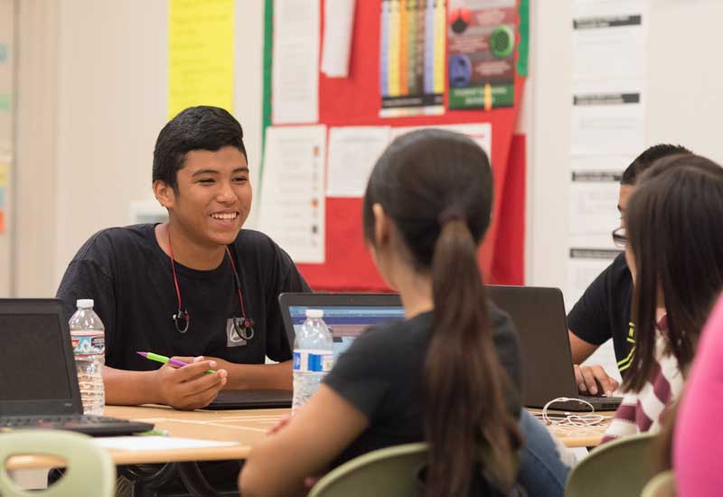 Photo of group of students seated at table in discussion
