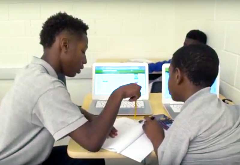Photo of two students working together with notebooks and laptop computers
