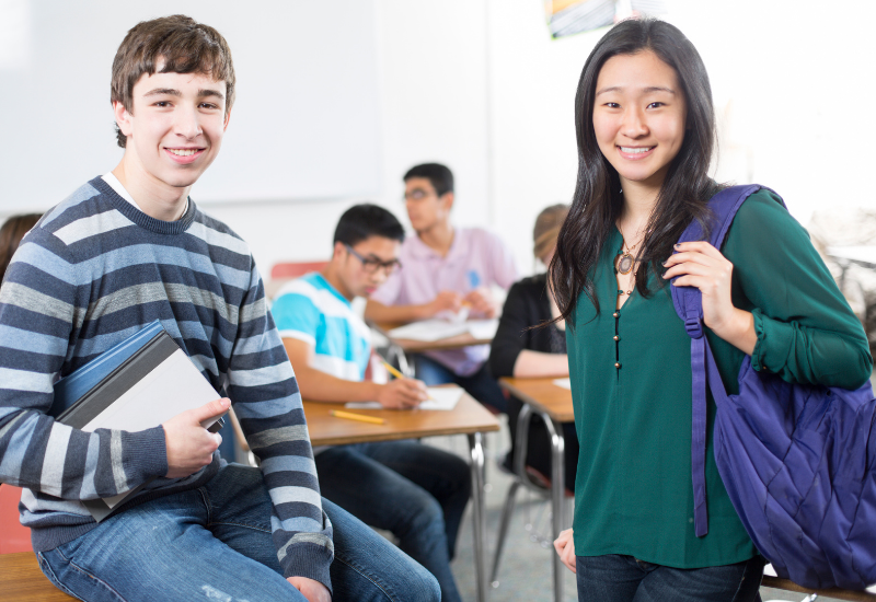Two high school students standing, smiling at camera
