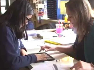 Photo of teacher and student in conference using tablet device
