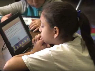 Photo closeup of student reading on her tablet device
