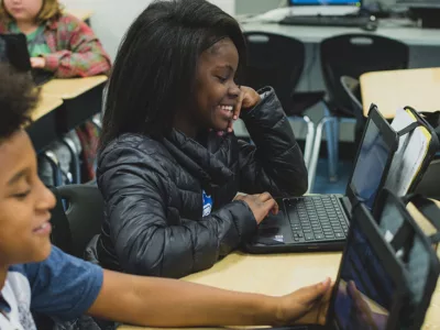 Student smiles as she looks at laptop
