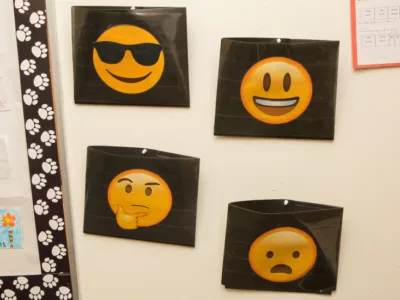 Four folders placed on a wall, each with a different emoji face

