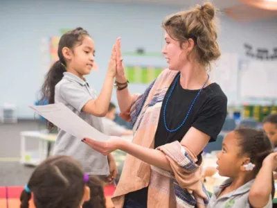 Photo of student and teacher giving each other high-five celebrating sucess
