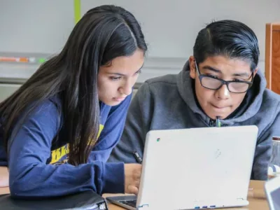 Photo of two students working together in front of laptop
