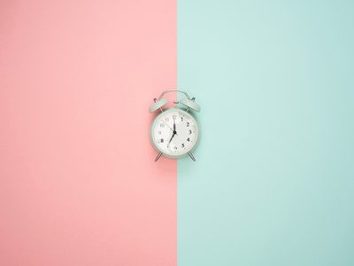 Alarm clock sitting on top of a two-toned pink and turquoise background
