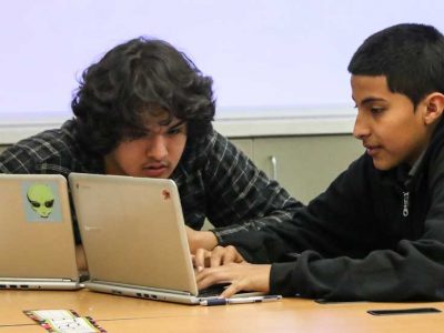 Photo of two students working together in front of laptop
