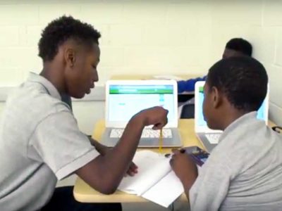 Photo of two students working together with notebooks and laptop computers
