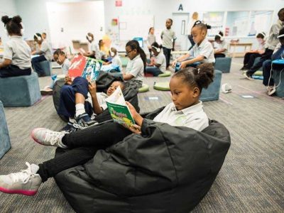 Photo of classroom with students reading on beanbags and working on devices at desks
