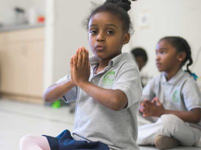 Photo closeup of student with hands together at heart center for mindfulness
