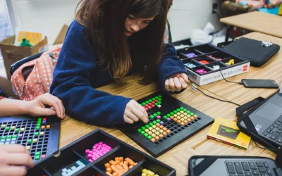 Student placing colorful blocks into black tray