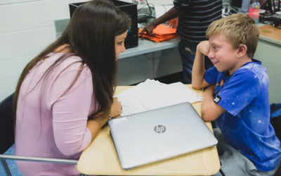 Student speaks with teacher, smiling