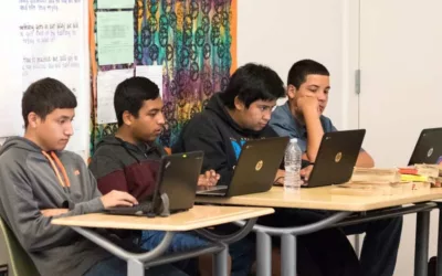 Photo of group of students working on laptops at classroom table