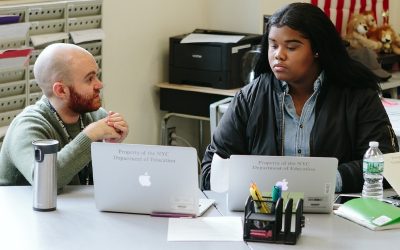 Teacher speaks to student as she looks at laptop
