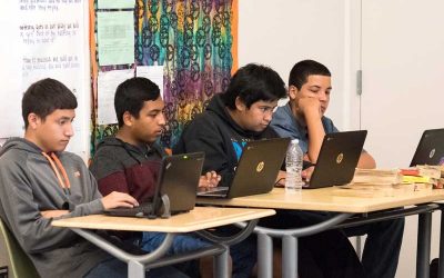 Photo of group of students working on laptops at classroom table