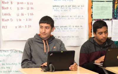 Photo of two students seated with laptops in front