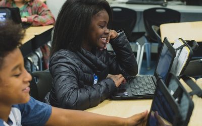 Student smiles as she looks at laptop
