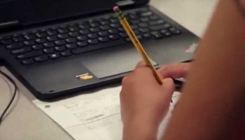 Photo closeup of student working in notebook with laptop on desk