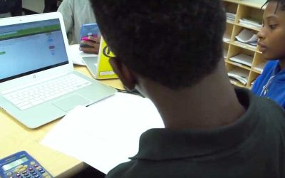 Photo of students working together with notebook and devices