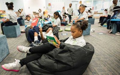 Photo of classroom with students reading on beanbags and working on devices at desks