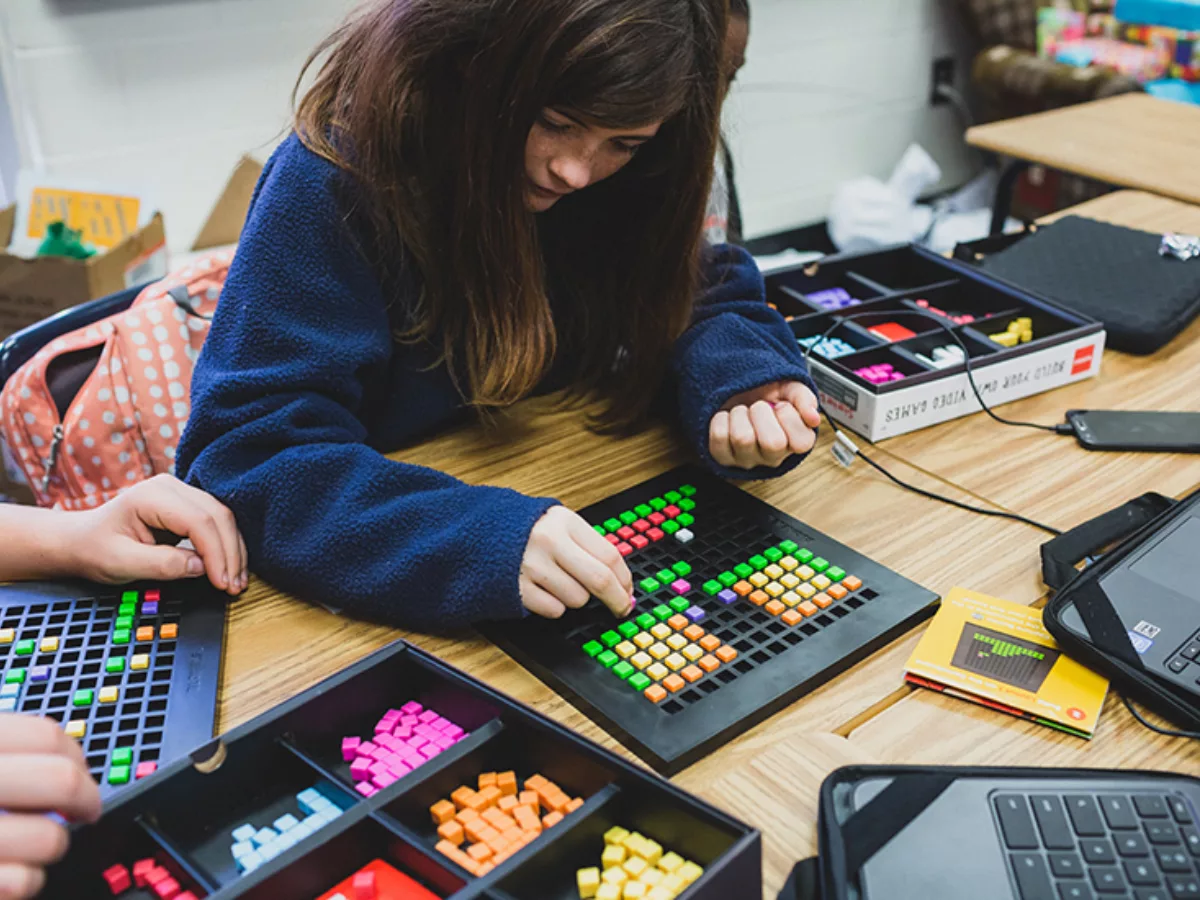 Student placing colorful blocks into black tray