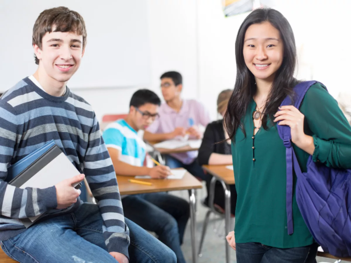 Two high school students standing, smiling at camera
