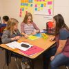 Teacher works with pair of students at small desk
