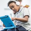 Elementary student looks closely at tablet, wears headphones